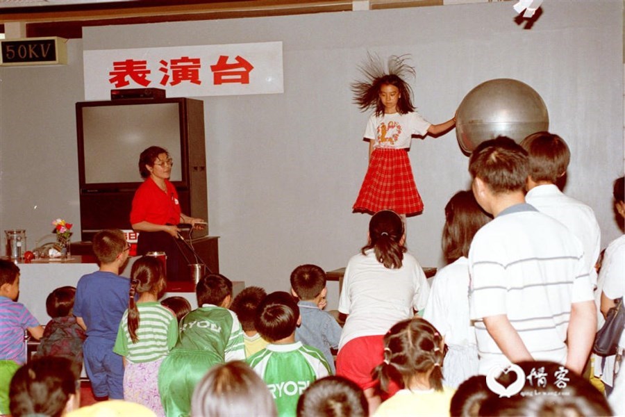 1998年5月31日，许多小学生来到中国科技馆学习科技知识，欢庆“六一”儿童节。这是科技馆工作人员帮助儿童体会人体静电反应。